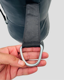 Hand holding a metal D-ring with a strap against a gray background