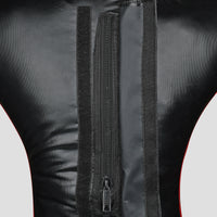 Close-up of the back of a black faux-leather or leather garment, showing a central vertical zipper, hook-and-loop fastening strips, and a thin red piping accent along the sides.