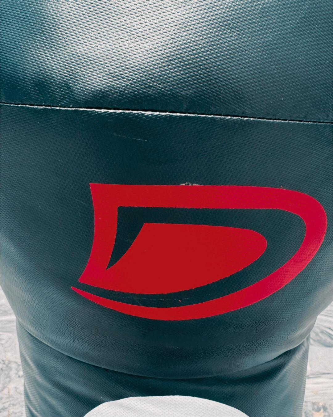 Close-up of a green leather product with a red logo on a textured surface.