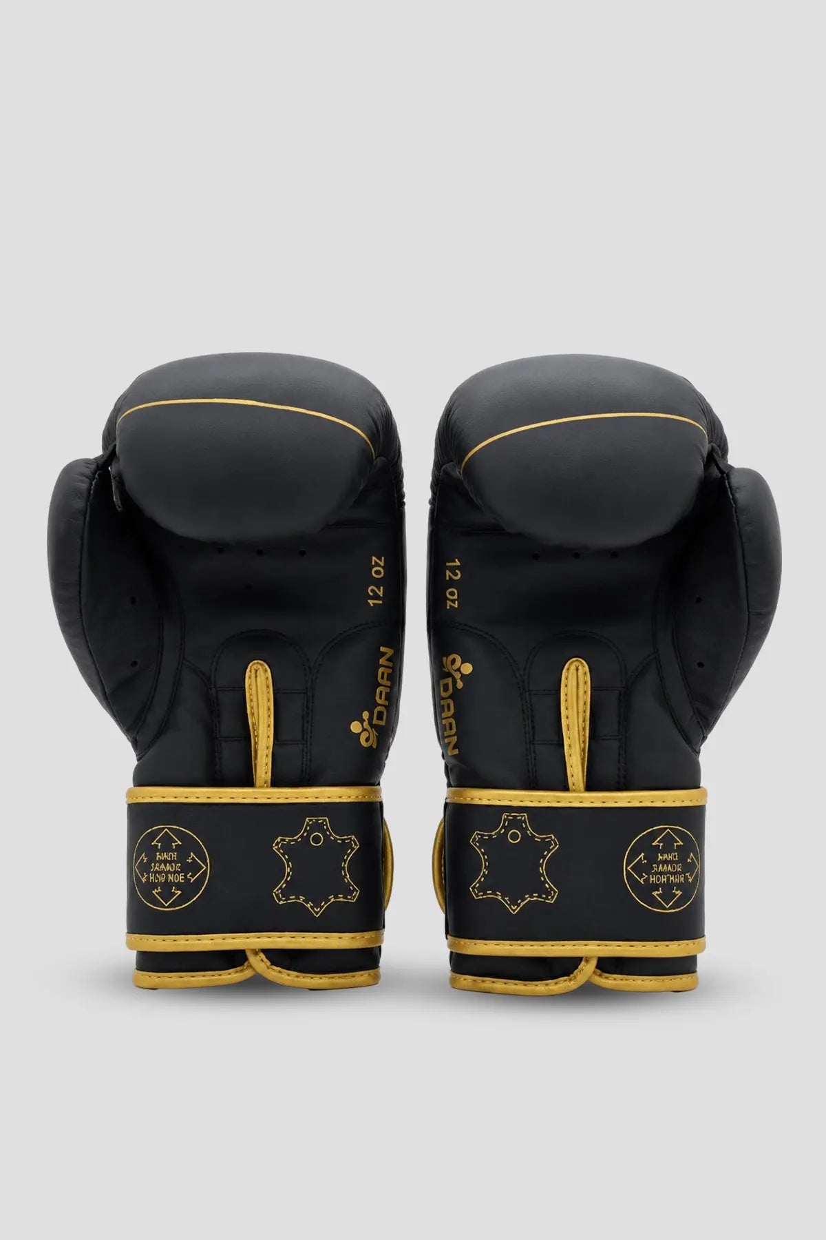 Palm-side view of black and gold DAAN boxing gloves showing inner padding and reinforced wrist straps.