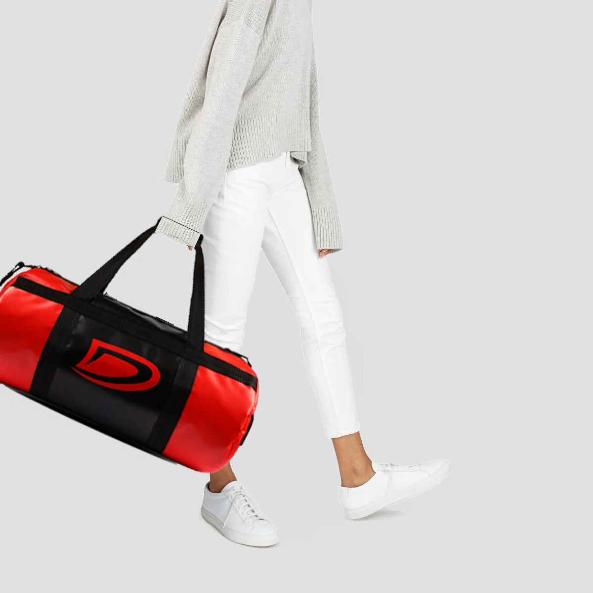 Person holding a red and black duffel bag on a light gray background