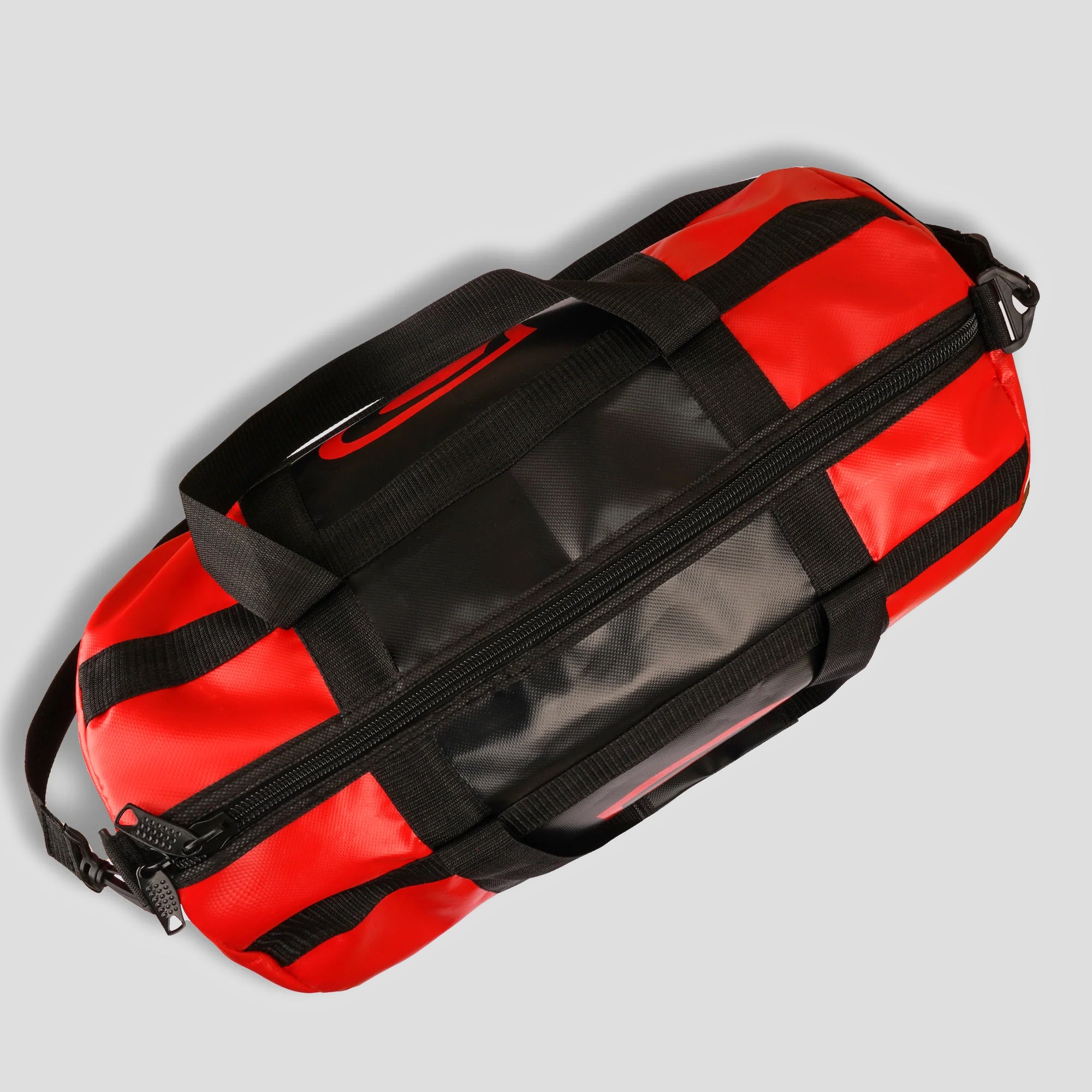 Red duffel bag with black straps on a light gray background