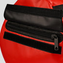 Close-up of a red bag with black zipper and strap on a light gray background
