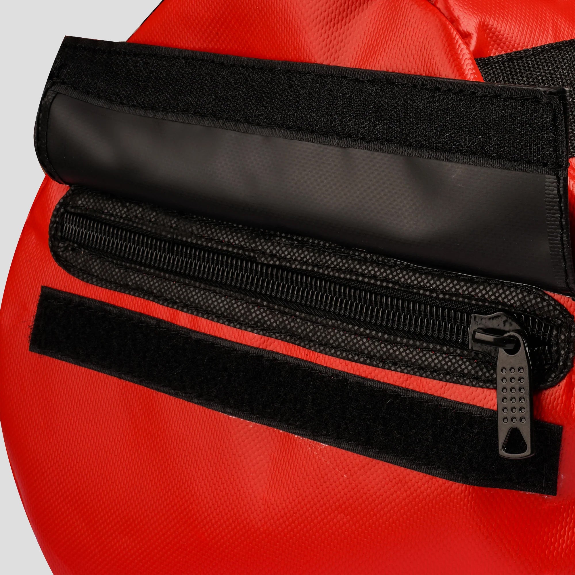 Close-up of a red bag with black zipper and strap on a light gray background