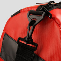 Close-up of a red bag with black straps and zippers on a light gray background