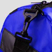 Close-up of a blue bag with black zippers and straps on a light gray background