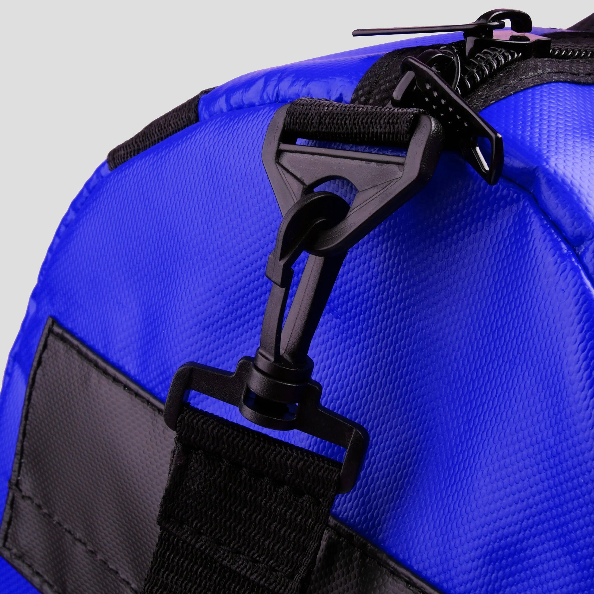 Close-up of a blue bag with black zippers and straps on a light gray background