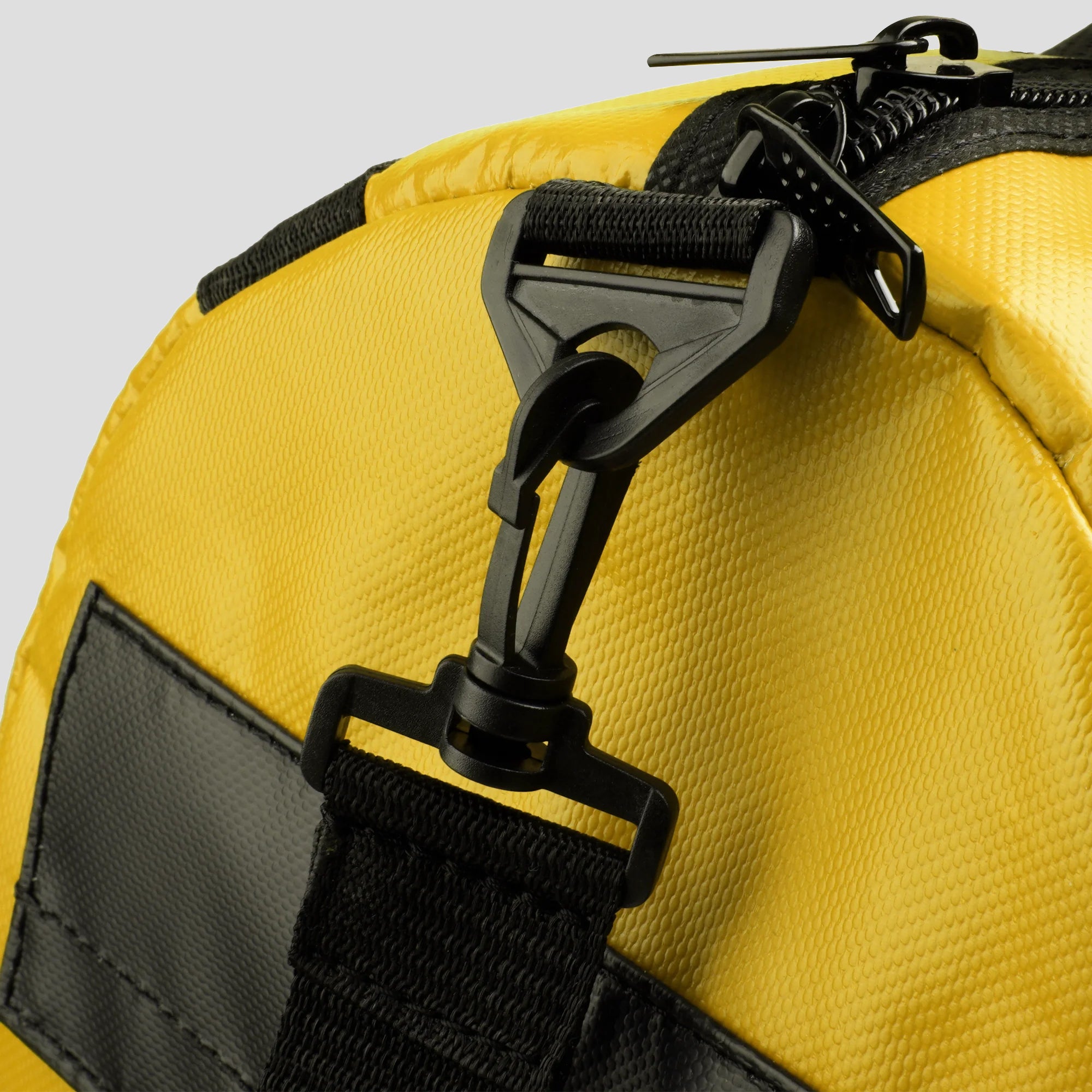 Close-up of a yellow bag with black straps and zipper on a light gray background